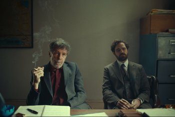Movie still from “Argentina, 1985” (2022), directed by Santiago Mitre – Two men sitting at a table in front of each other; Medium shot, Low angle