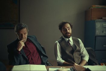 Movie still from “Argentina, 1985” (2022), directed by Santiago Mitre – Two men sitting at a table in front of papers; Medium shot, Over the shoulder angle