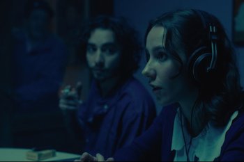 Movie still from “Argentina, 1985” (2022), directed by Santiago Mitre – Two people sitting in a room with headphones on; Close Up shot, Over the shoulder angle