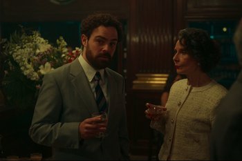 Movie still from “Argentina, 1985” (2022), directed by Santiago Mitre – A man and a woman standing next to each other holding drinks; Medium shot, Over the shoulder angle