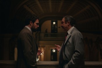 Movie still from “Argentina, 1985” (2022), directed by Santiago Mitre – Two men in business suits talking to each other in a building; Medium shot, Over the shoulder angle