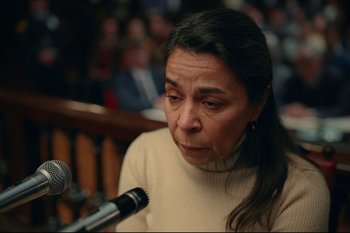 Movie still from “Argentina, 1985” (2022), directed by Santiago Mitre – A woman is sitting at a microphone in front of a crowd; Close Up shot, High angle