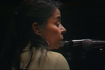 Movie still from “Argentina, 1985” (2022), directed by Santiago Mitre – A woman is holding a microphone up to her mouth; Close Up shot, High angle