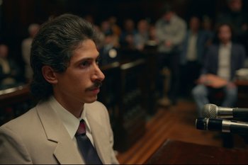 Movie still from “Argentina, 1985” (2022), directed by Santiago Mitre – A man in a suit and tie sitting in front of an audience; Close Up shot, High angle