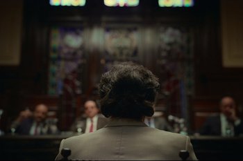 Movie still from “Argentina, 1985” (2022), directed by Santiago Mitre – A man in a suit and tie in front of two other men; Medium shot, Over the shoulder angle