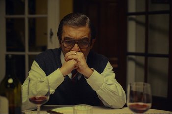 Movie still from “Argentina, 1985” (2022), directed by Santiago Mitre – An older man sitting at a table with a glass of red wine; Close Up shot, Over the shoulder angle
