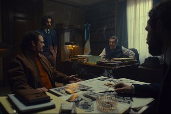 Movie still from “Argentina, 1985” (2022), directed by Santiago Mitre – A group of men sitting at a table in a room; Wide shot, Low angle