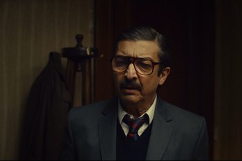Movie still from “Argentina, 1985” (2022), directed by Santiago Mitre – A man in a suit and tie wearing glasses; Close Up shot, Over the shoulder angle
