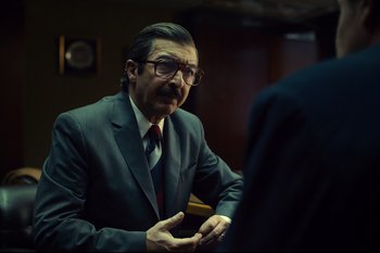 Movie still from “Argentina, 1985” (2022), directed by Santiago Mitre – An older man wearing a suit and glasses talking to someone; Medium shot, Over the shoulder angle