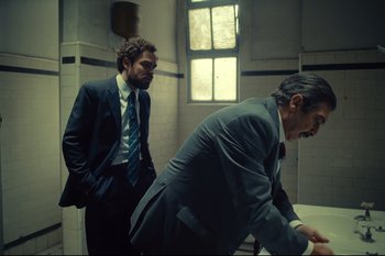 Movie still from “Argentina, 1985” (2022), directed by Santiago Mitre – Two men in suits and ties standing in a room; Medium shot, Low angle