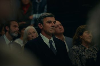 Movie still from “Argentina, 1985” (2022), directed by Santiago Mitre – A man in a suit and tie in a crowd of people; Medium shot, Over the shoulder angle