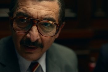 Movie still from “Argentina, 1985” (2022), directed by Santiago Mitre – An older man wearing glasses and a suit; Close Up shot, Over the shoulder angle