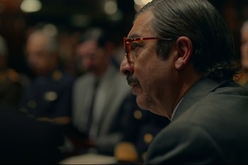 Movie still from “Argentina, 1985” (2022), directed by Santiago Mitre – An older man wearing a suit and glasses looking to his left; Close Up shot, Over the shoulder angle