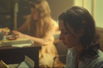 Movie still from “Argentina, 1985” (2022), directed by Santiago Mitre – Two women sitting at a table in front of a laptop; Medium shot, Over the shoulder angle