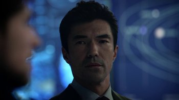 Movie still from “Salvation” (2017), created by Elizabeth Kruger – A person wearing a suit and tie; Close Up shot, Over the shoulder angle