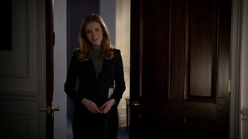 Movie still from “Salvation” (2017), created by Elizabeth Kruger – A woman in a black suit standing in front of a door; Medium shot, Over the shoulder angle