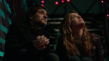 Movie still from “Salvation” (2017), created by Elizabeth Kruger – A man and a woman sitting next to each other holding wii remotes; Medium shot, Low angle