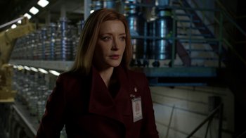 Movie still from “Salvation” (2017), created by Elizabeth Kruger – A woman in a red coat is standing in a room; Close Up shot, Over the shoulder angle