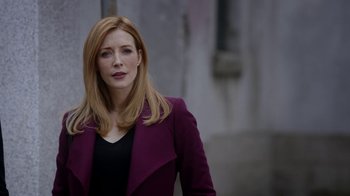 Movie still from “Salvation” (2017), created by Elizabeth Kruger – A woman in a black top and a purple jacket; Close Up shot, Low angle