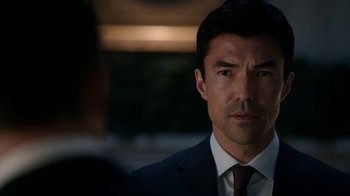 Movie still from “Salvation” (2017), created by Elizabeth Kruger – A person wearing a suit and tie; Close Up shot, Over the shoulder angle