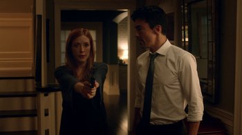 Movie still from “Salvation” (2017), created by Elizabeth Kruger – A man and a woman holding a gun in a room; Medium shot, Over the shoulder angle