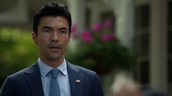 Movie still from “Salvation” (2017), created by Elizabeth Kruger – A person wearing a suit and tie; Close Up shot, Over the shoulder angle