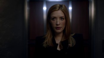 Movie still from “Salvation” (2017), created by Elizabeth Kruger – A woman in a black jacket standing in a dark room; Close Up shot, Low angle
