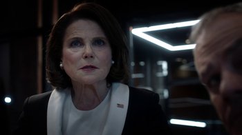 Movie still from “Salvation” (2017), created by Elizabeth Kruger – An older woman in a black jacket and white shirt; Close Up shot, Over the shoulder angle