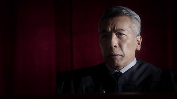 Movie still from “Salvation” (2017), created by Elizabeth Kruger – An older man in a suit and tie looking at the camera; Close Up shot, Low angle