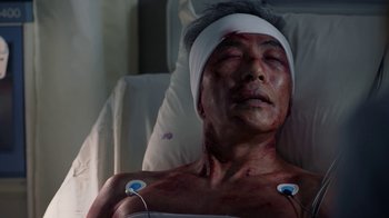 Movie still from “Salvation” (2017), created by Elizabeth Kruger – An asian man with a bandage on his head; Close Up shot, Overhead angle