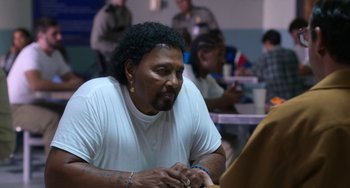 Movie still from “Sandy Wexler” (2017), directed by Steven Brill – A man sitting at a table looking at his cell phone; Medium shot, Over the shoulder angle