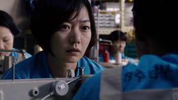 Movie still from “Sense8” (2015), directed by Tom Tykwer – A woman in a blue shirt is looking at the camera; Close Up shot, Over the shoulder angle