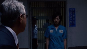 Movie still from “Sense8” (2015), directed by Tom Tykwer – A woman in a blue shirt is standing in front of a jail cell; Medium shot, Over the shoulder angle