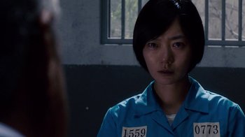 Movie still from “Sense8” (2015), directed by Tom Tykwer – A woman in a blue prison uniform looking at the camera; Close Up shot, Over the shoulder angle