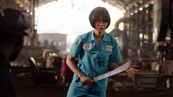Movie still from “Sense8” (2015), directed by Tom Tykwer – A person holding a large knife in a warehouse; Medium shot, Low angle