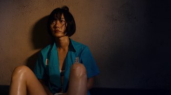 Movie still from “Sense8” (2015), directed by Tom Tykwer – A woman sitting on the ground wearing a blue shirt; Medium shot, High angle