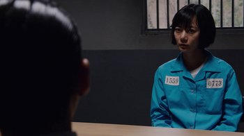 Movie still from “Sense8” (2015), directed by Tom Tykwer – A person sitting at a table in a jail cell; Close Up shot, Over the shoulder angle