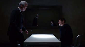 Movie still from “Sense8” (2015), directed by Tom Tykwer – Two men in a dark room looking at a table; Medium shot, Over the shoulder angle