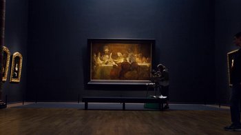 Movie still from “Sense8” (2015), directed by Tom Tykwer – A painting of a group of people sitting in front of a painting; Wide shot, Low angle