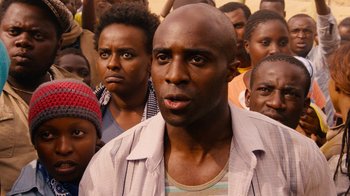 Movie still from “Sense8” (2015), directed by Tom Tykwer – A group of people standing around each other in front of a building; Close Up shot, Over the shoulder angle