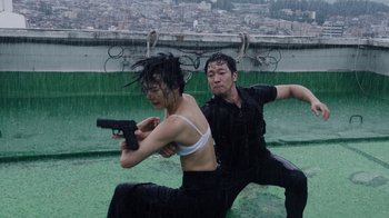 Movie still from “Sense8” (2015), directed by Tom Tykwer – A man and a woman are holding guns in the rain; Medium shot, Low angle