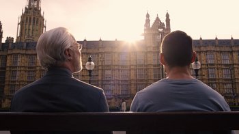 Movie still from “Sense8” (2015), directed by Tom Tykwer – Two men sitting on a bench looking at a building; Medium shot, Over the shoulder angle