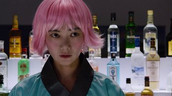 Movie still from “Sense8” (2015), directed by Tom Tykwer – A person with pink hair standing in front of a bar; Close Up shot, Over the shoulder angle