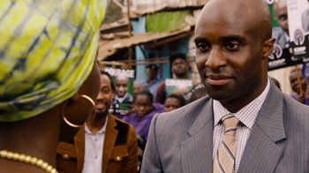 Movie still from “Sense8” (2015), directed by Tom Tykwer – A man wearing a suit and tie standing next to a crowd; Close Up shot, Over the shoulder angle