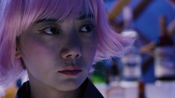 Movie still from “Sense8” (2015), directed by Tom Tykwer – A person wearing a pink wig; Close Up shot, Over the shoulder angle