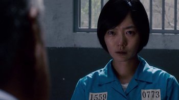 A woman in a blue prison uniform looking at the camera