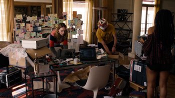 Movie still from “Sense8” (2015), directed by Tom Tykwer – A man and a woman working on a computer in a cluttered room; Wide shot, High angle