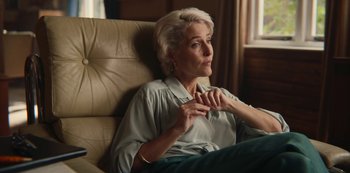 Movie still from “Sex Education” (2019), created by Laurie Nunn – An older woman sitting in a chair with her hand on her chin; Close Up shot, Over the shoulder angle