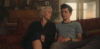 Movie still from “Sex Education” (2019), created by Laurie Nunn – A man and a woman sitting on a couch together; Medium shot, Over the shoulder angle