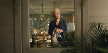 Movie still from “Sex Education” (2019), created by Laurie Nunn – An older woman standing in front of a bathroom mirror; Medium shot, Low angle